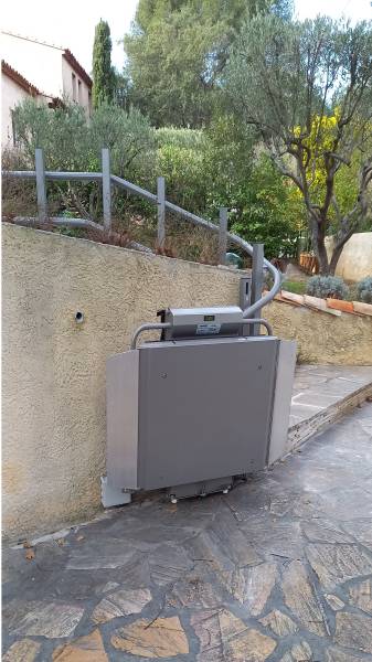 Plateforme monte escalier en position d'attente sur son point de charge automatique des batteries